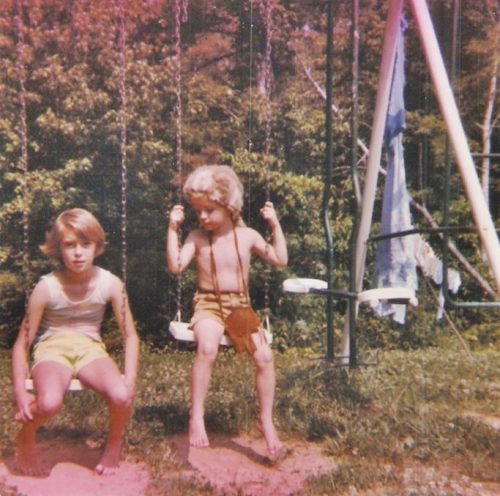 Boy in coonskin cap and girl on swingset