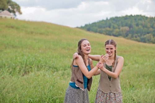 two girls laughing in a field of grass