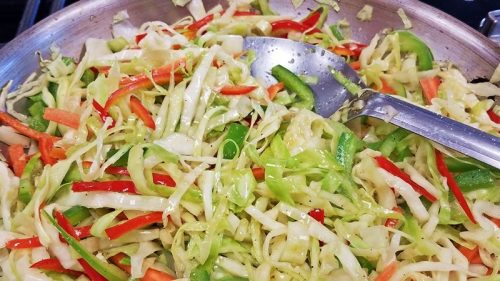 pan full of fried cabbage peppers and onions