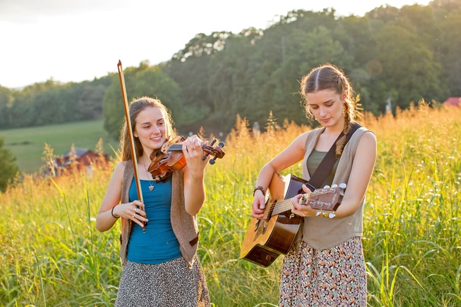 The Pressley Girls standing in a field of grass smiling with instruments
