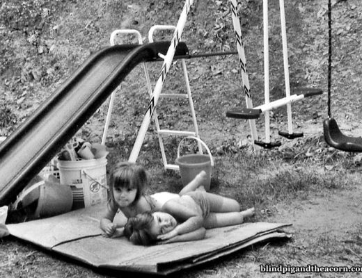 two girls laying by a swingset