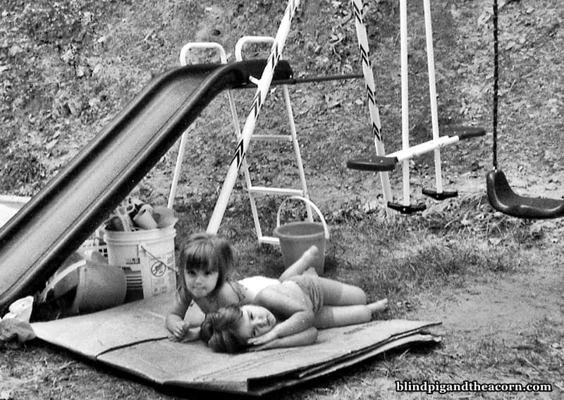two girls laying by a swingset