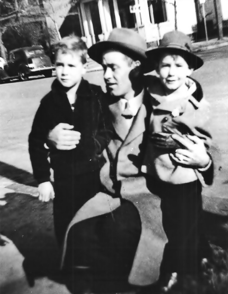 a man and two boys standing in street