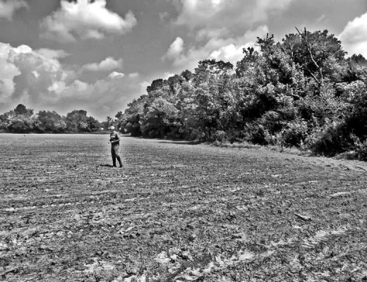 man standing in a plowed field
