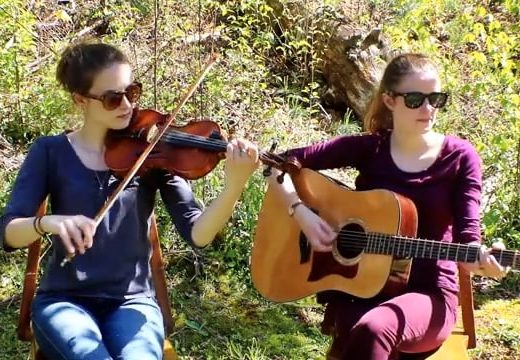 two girls sitting outside with fiddle and guitar