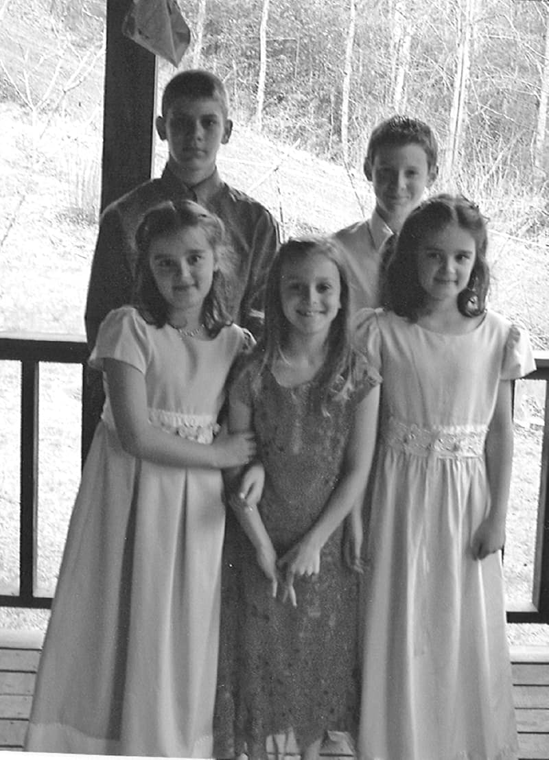 three girls and two boys standing on porch