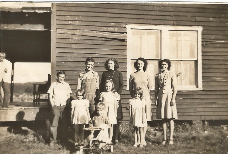 old picture of family standing by house