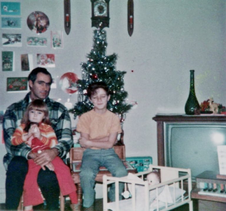 man girl and boy sitting in front of small christmas tree in appalachia