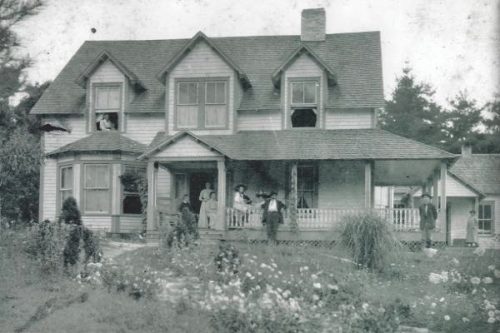 Picture of old house with people standing on porch