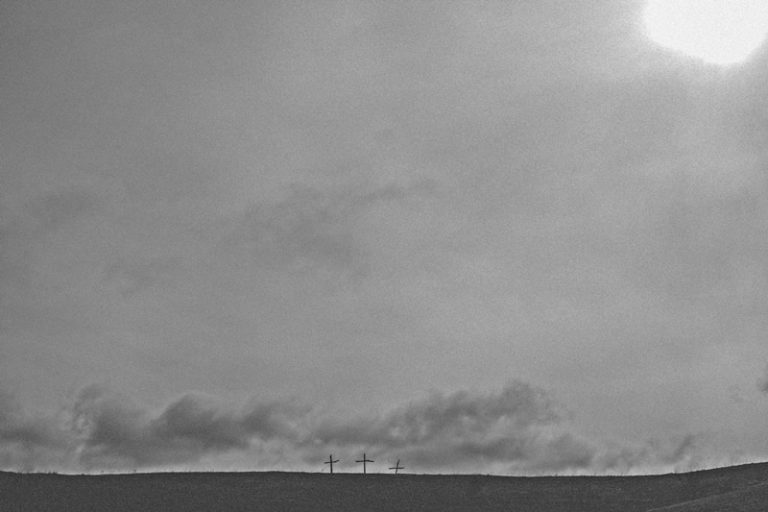 photo of three crosses under dark skies