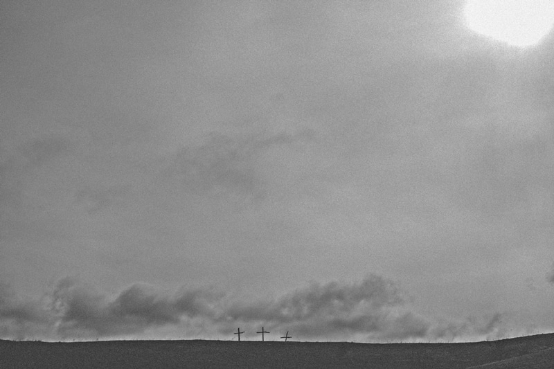 photo of three crosses under dark skies