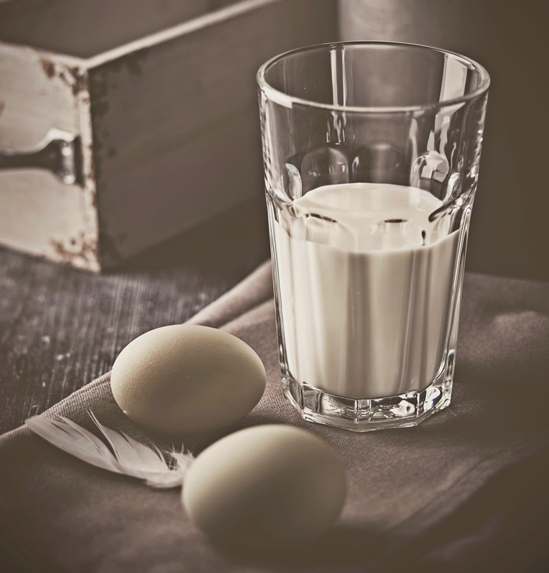 glass of milk and two eggs on table