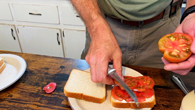 man making tomato sandwich