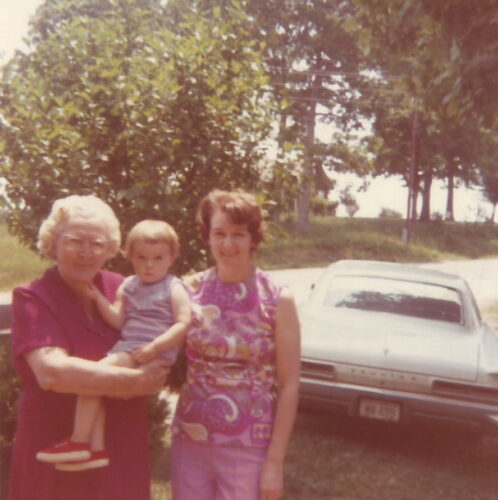 three generations of women standing by car
