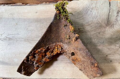 rusty plow point on wood bench