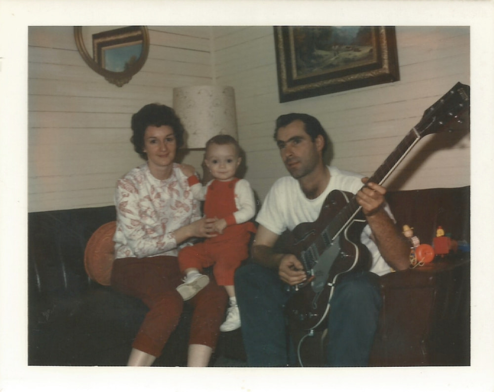 Man with guitar sitting with woman and boy