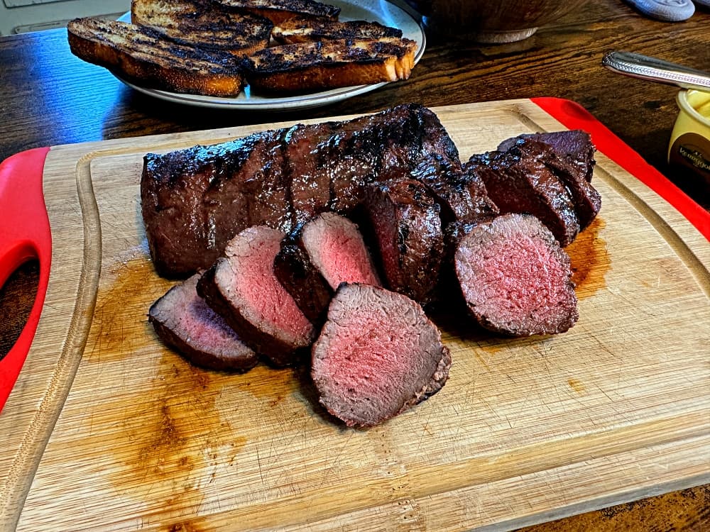 sliced grilled deer meat on cutting board