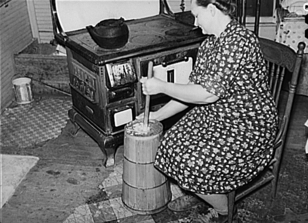 woman churning butter by stove