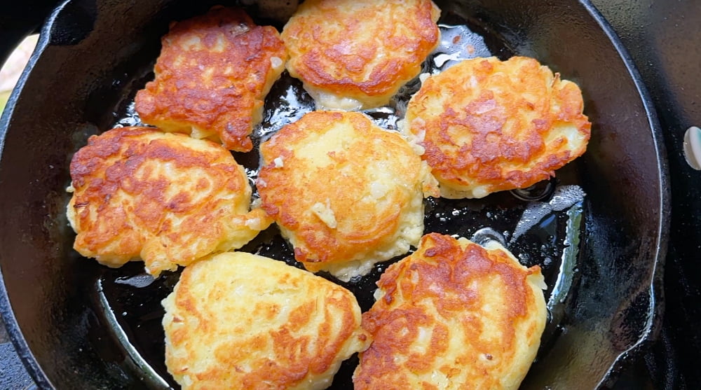 cast iron pan of potato cakes cooking