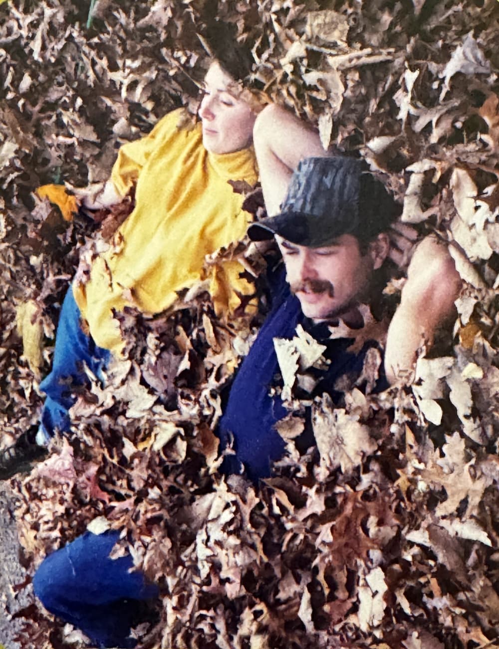 man and woman laying in leaves