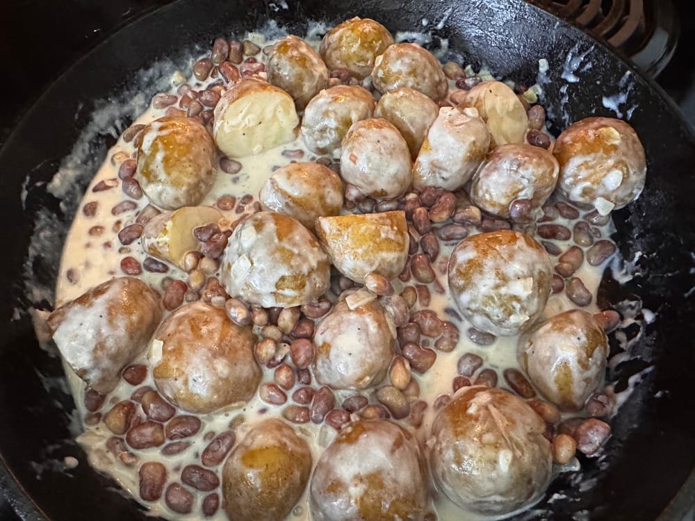 frying pan with creamed peas and new potatoes