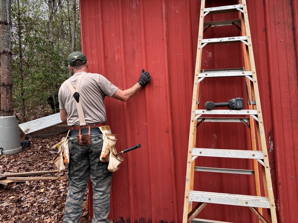 man putting up metal wall