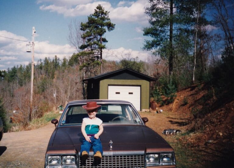 small boy sitting on old car